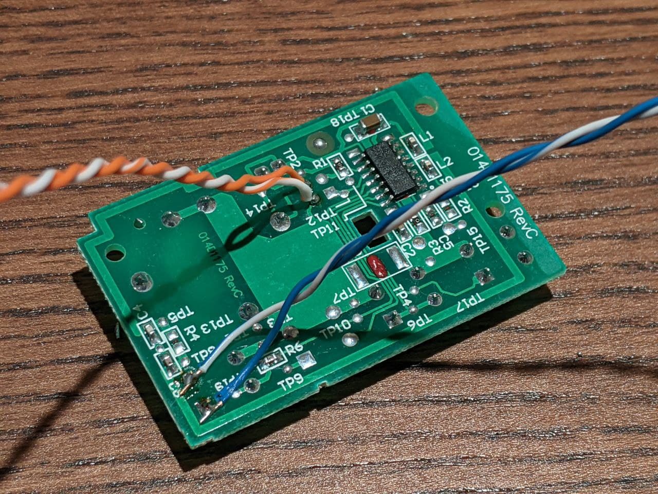 a closeup of the green PCB with two wires soldered to the battery terminals and two to the button pins